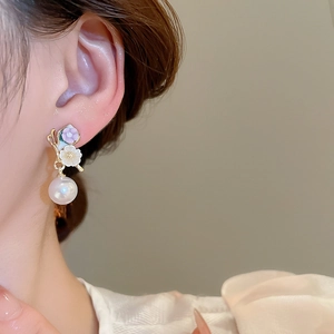 Gros plan de boucles d'oreilles fleurs dorées avec pétales lavande et perles blanches