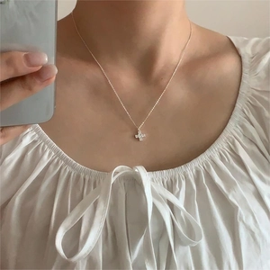 Close-up of minimalist 925 sterling silver cross necklace worn on a woman's neck