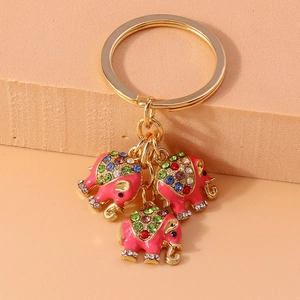 Detail von drei rosa Elefantenanhängern mit bunten Strasssteinen auf goldener Kette