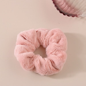 Dettaglio dell'elastico per capelli in peluche rosa con morbida trama in finta pelliccia