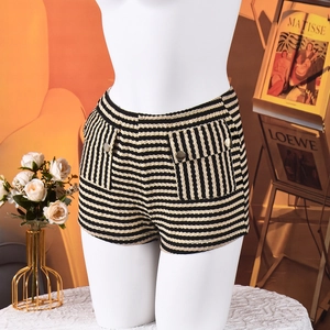 Detail van tweed shorts met hoge taille, zwart-gouden strepen en zakken met metalen knoop