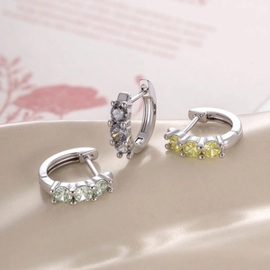 Silver hoop earrings with grey, yellow, and green zircon stones on soft background