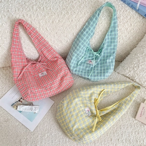 Detailed view of checkered canvas tote bags with bow ties in pink, blue and yellow colors