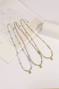 Three-strand peridot and tourmaline beaded necklaces with unique metal pendants on white