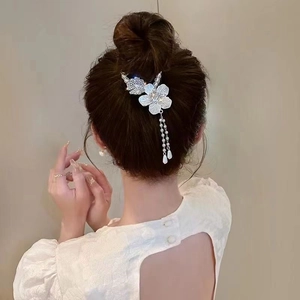 Dettaglio del fermaglio a giglio con nappe e perle su un'elegante acconciatura raccolta