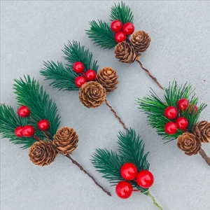 Christmas picks with red berries, pine needles, and pine cones on a grey background