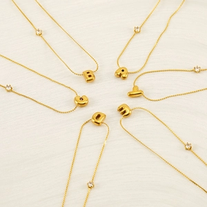 Golden bubble letter pendant necklace with sparkling zircon accent in a circular layout