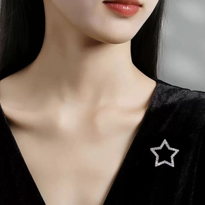 Elegant star-shaped brooch pin with sparkling rhinestones on black velvet fabric