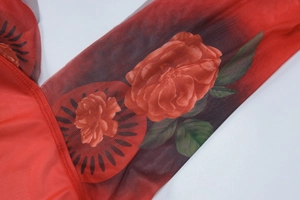 Dettaglio del tessuto in rete trasparente con stampa floreale di rose rosse e cuciture