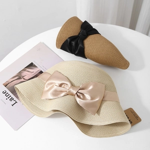 Détail de chapeaux de soleil élégants en paille avec nœuds en soie, style de plage pliable