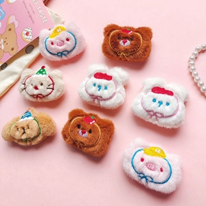 Close-up of assorted plush cartoon animal pins with delicate embroidery on pink surface