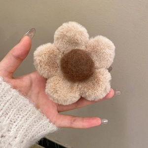 Close-up of cute plush daisy hair claw with soft beige petals and brown center
