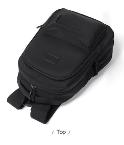 Top-down view of black student backpack showing multiple zippers and padded handle