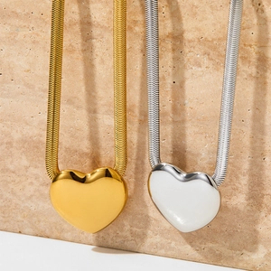 Elegant gold and silver heart pendant necklaces displayed on a minimalist stone base