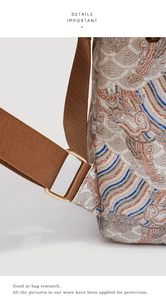 Detailed close-up of cream jacquard fabric with golden metal rings and brown strap