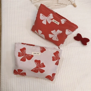 Detailed view of canvas makeup bags with red bow prints and simple wish label