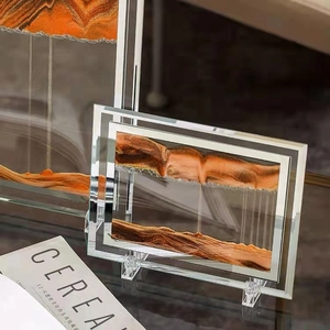 Detail of liquid sand art decor with orange layered mountains and silver frame