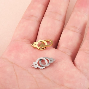 Interlocked stainless steel handcuffs pendant in gold and silver held on hand