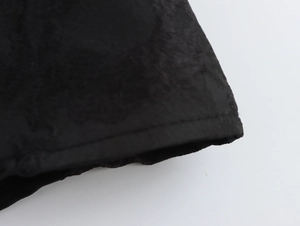 Makrodetail aus schwarzem Prägegewebe mit eleganter Blumenstruktur und feiner Naht