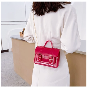 Detailed view of a trendy red jelly Cambridge crossbody bag worn by a model in white
