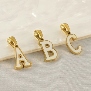 Detailed macro view of gold alphabet pendants A, B, and C with white enamel inlay