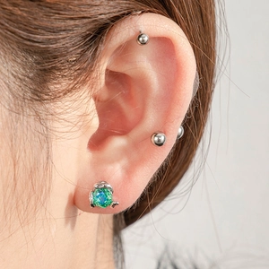 Silver snake-claw stud earring with a large green rose-cut gemstone on a model's ear