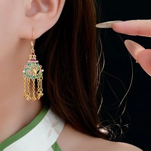 Détail de boucles d'oreilles cœur en or 18K avec émail cloisonné et longues franges