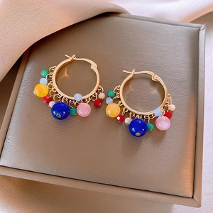 Macro detail of gold hoop earrings with multi-colored glass beads on jewelry box