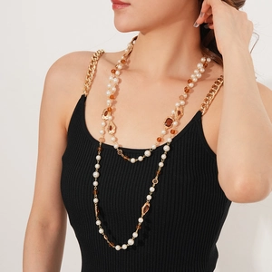 Detail of vintage double-layer pearl necklace with gold chains and amber beads on model
