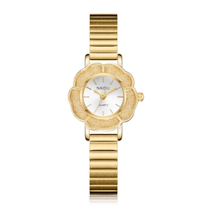 Détail d'une montre à quartz dorée en forme de fleur avec lunette texturée et bracelet métal