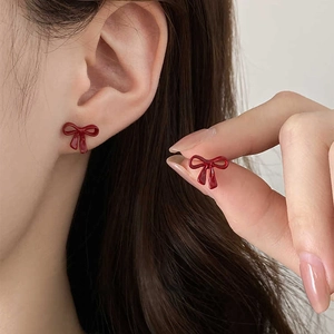 Elegant deep red bow stud earrings for women with polished finish on earlobe