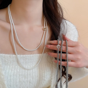 Detail of white and grey pearl necklaces with gold and silver OT buckles on a white sweater