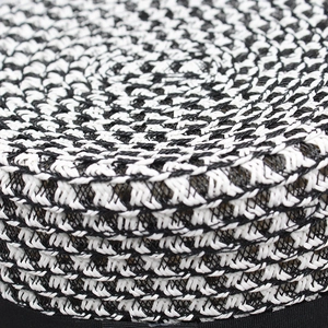 Macro view of woven straw hat featuring black and white geometric texture and ribbon edge