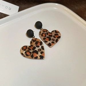 Detail of vintage leopard print heart-shaped earrings on a white jewelry tray