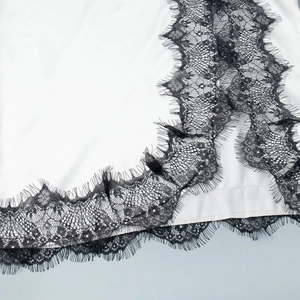 Détail de la dentelle noire sur le bord d'une robe en satin de soie blanc élégante