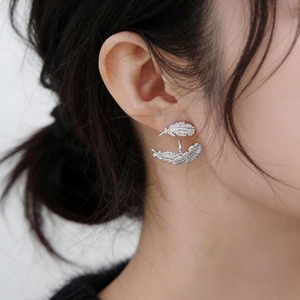 Elegant gold-plated feather earrings with cubic zirconia worn by a model in close-up