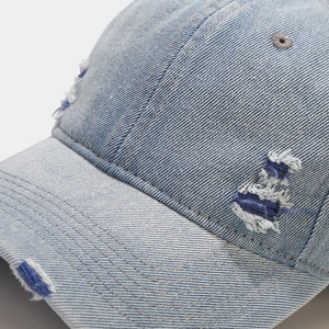 Gros plan sur une casquette en jean délavé avec détails usés et broderie de qualité