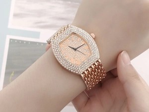 Detail of a rose gold tonneau watch with full rhinestone inlay and Roman numerals