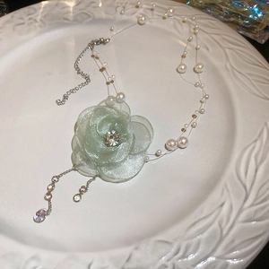 Detail of floral necklace with pale green fabric flower, white pearls and silver accents