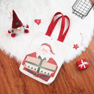 Christmas Santa canvas gift tote bag with red handles on a festive white fur background
