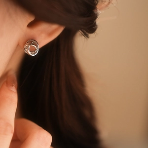 Gros plan d'une boucle d'oreille nœud torsadé argenté sur mannequin avec éclat