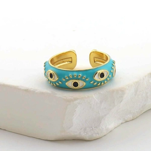 Dettaglio macro di un anello smaltato Evil Eye in oro su un espositore in pietra minimalista