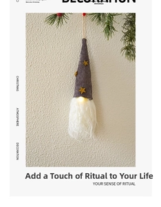 Detail of grey knitted Christmas gnome with gold stars and warm LED glowing beard