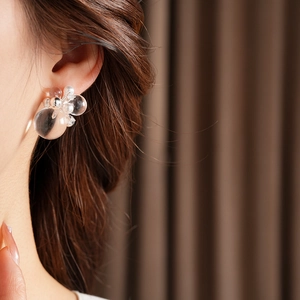 Close-up of elegant silver needle stud earrings with zircon and pearls worn by a model