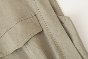Close-up of khaki linen fabric texture showing high-quality stitching on dress pockets