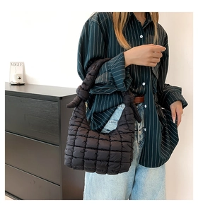 Close-up of black quilted puffer bag featuring a decorative knot on the shoulder strap