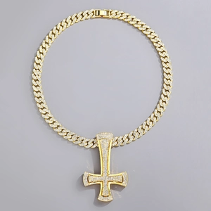 Close-up of golden Cuban chain with a large iced-out inverted cross pendant in detail