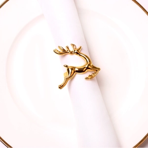 Close-up of golden reindeer metal napkin ring on a white napkin on a gold rimmed plate