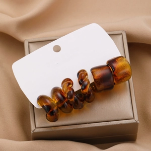Detailed view of amber resin twisted hoop earring on elegant champagne silk background