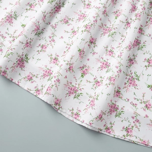 Close-up of lightweight white floral dress hem with delicate pink flower print detail